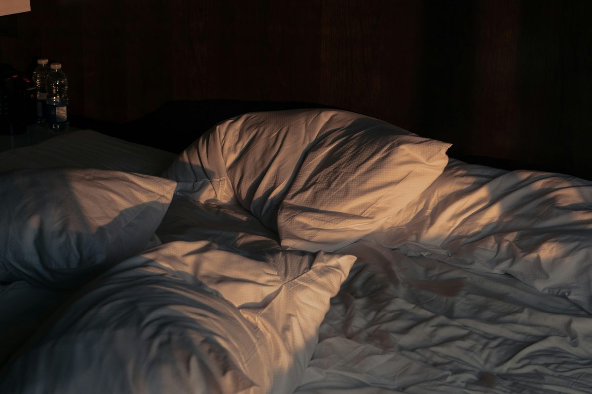 Rumpled cotton bedding on an unmade bed.
