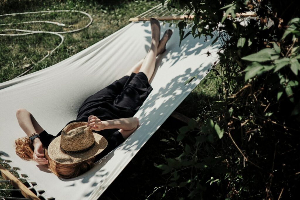 A woman resting in a hammock in dappled sunlight.