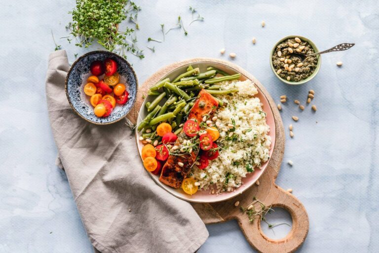 A balanced plate of vegetables, beans and protein on a wooden board.