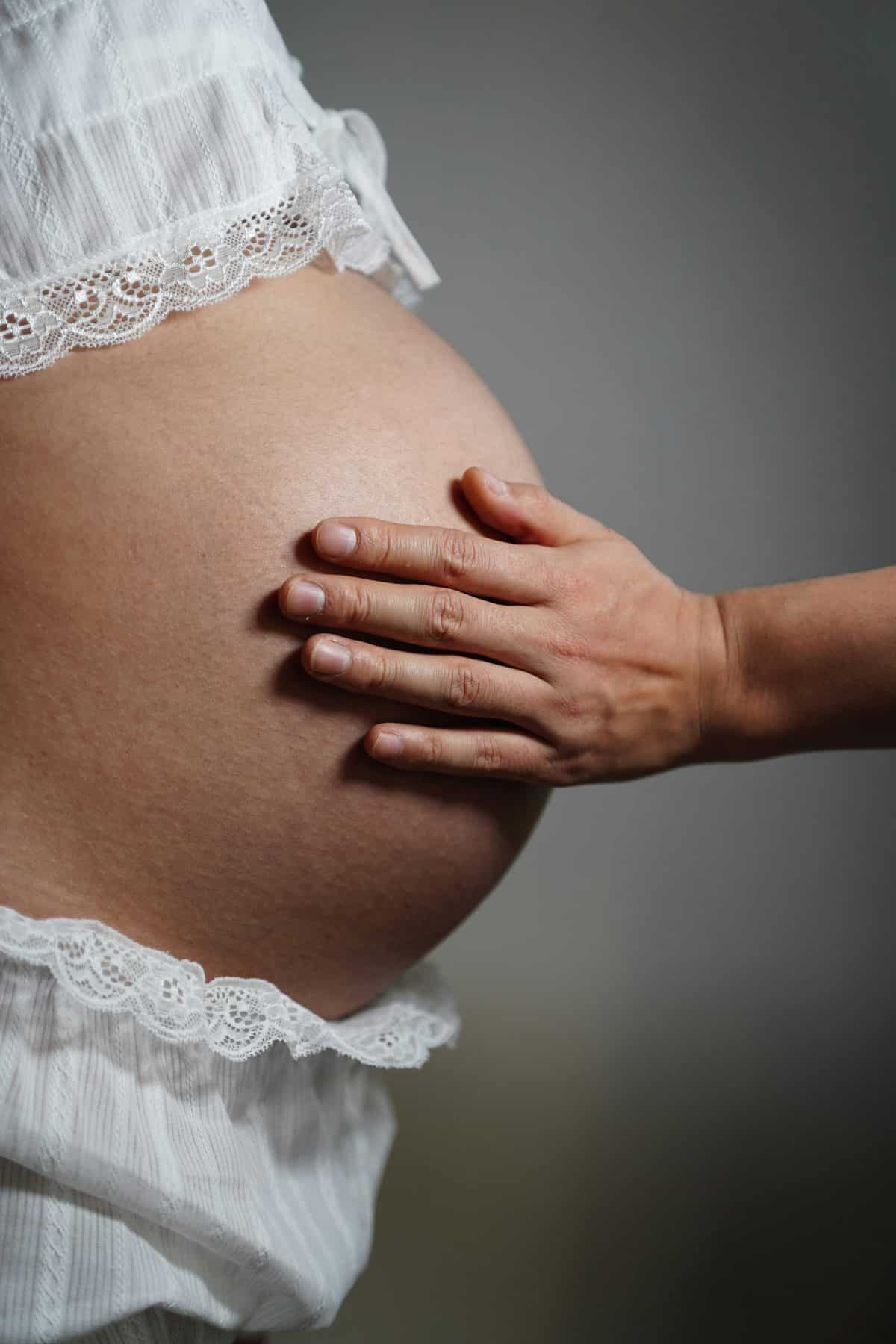 A hand resting gently on a pregnant bump.
