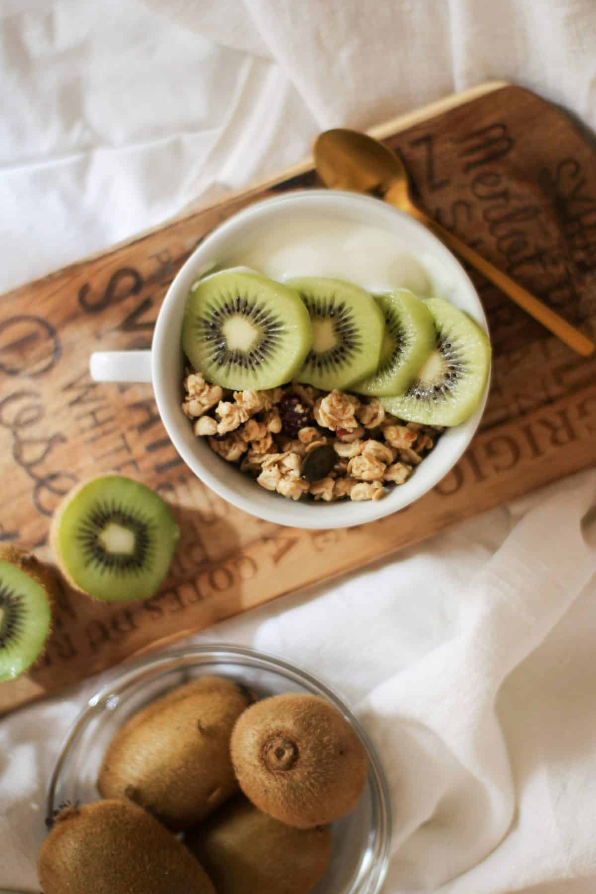 A bowl of yoghurt topped with kiwi and granola.