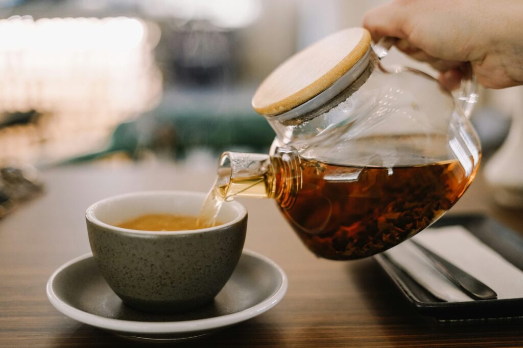 Loose herbal tea leaves and dried botanicals arranged beside a glass cup.