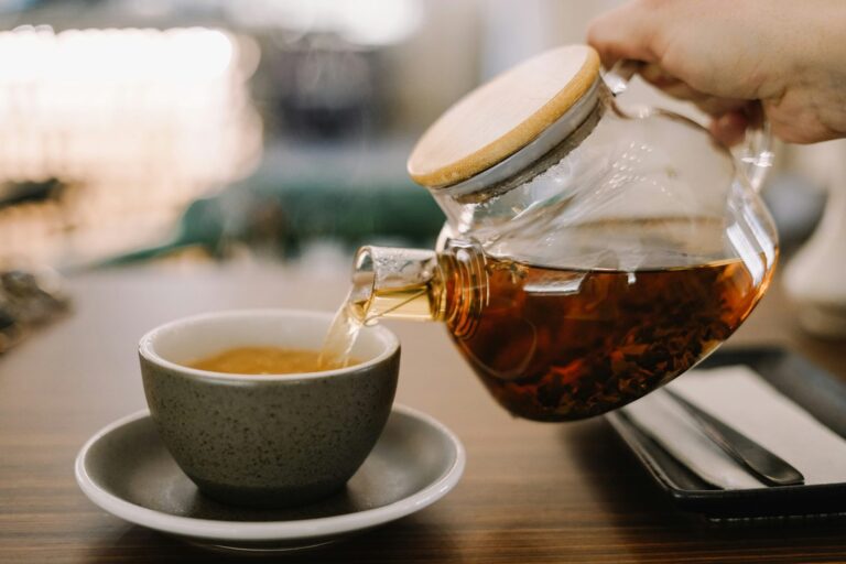 Loose herbal tea leaves and dried botanicals arranged beside a glass cup.