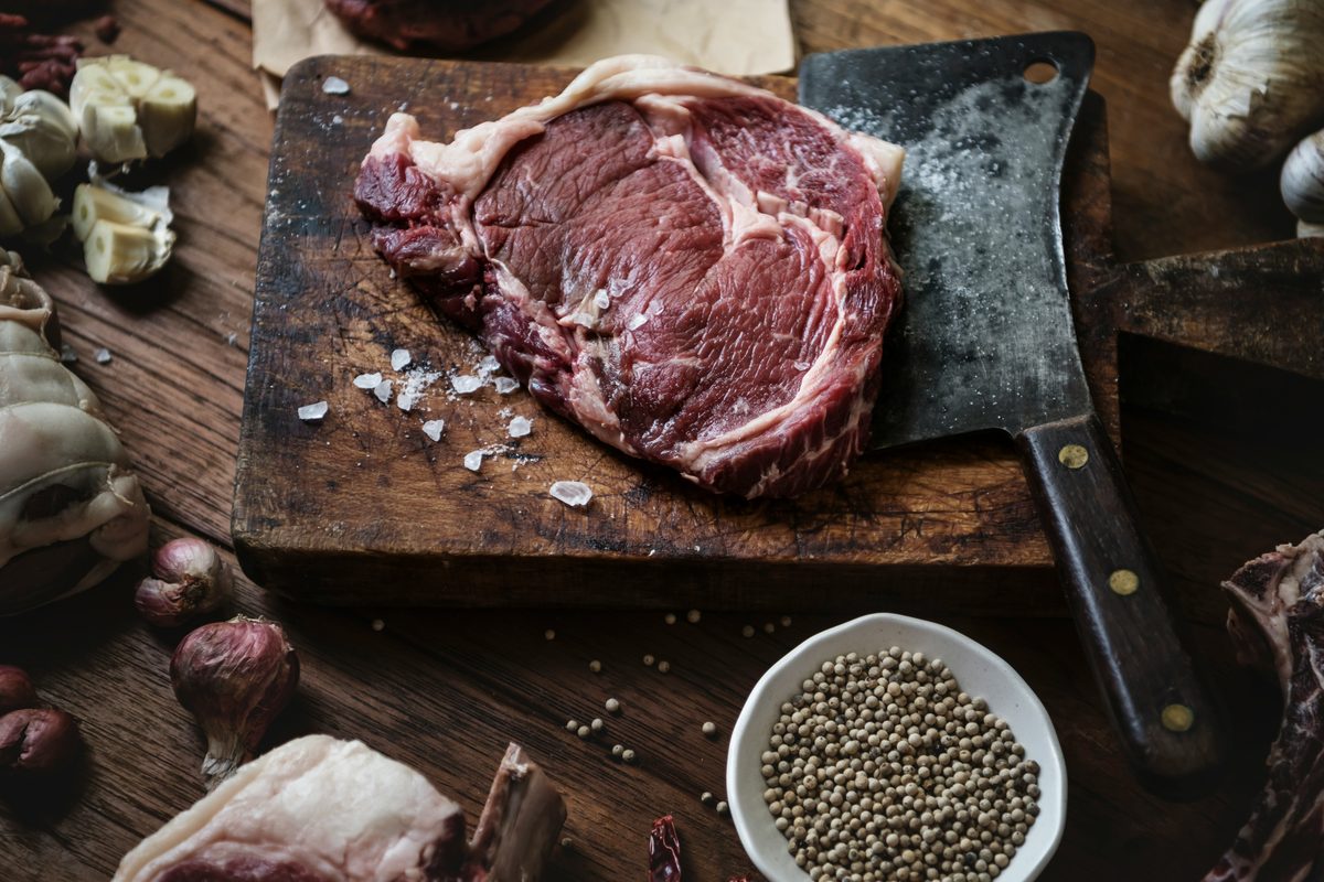 Iron-rich foods including red meat, lentils and garlic on a wooden board.