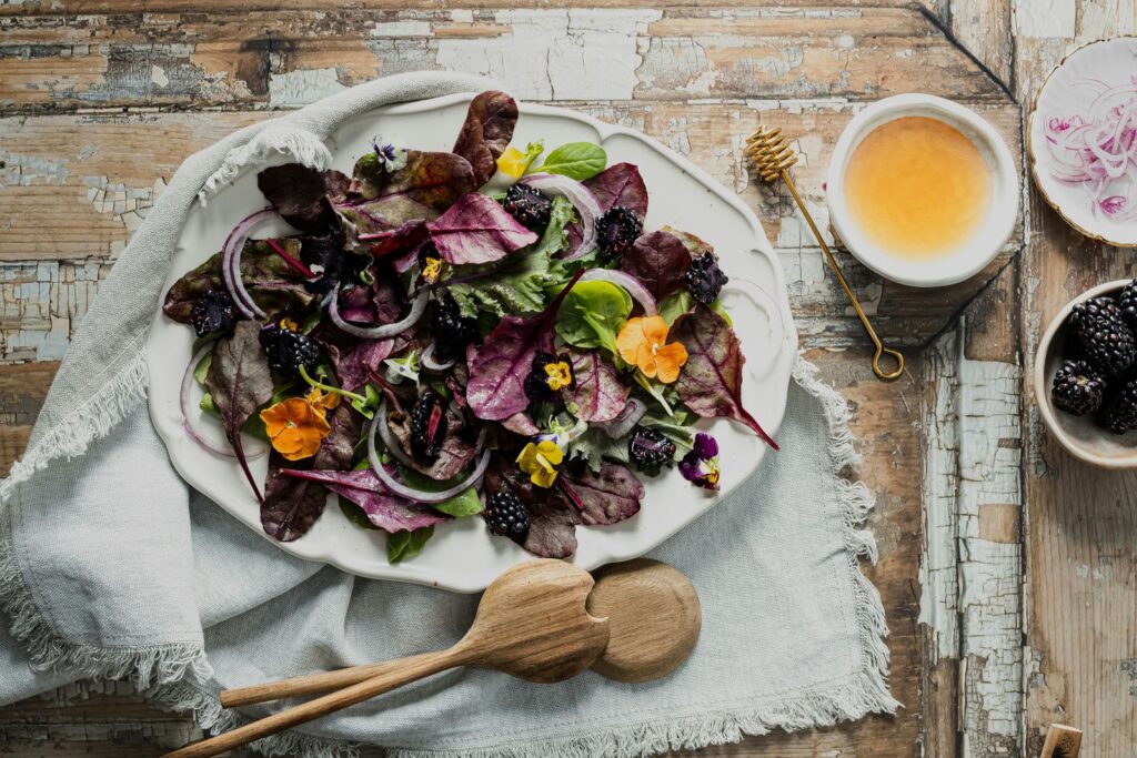 A colourful salad plate with leafy greens, seeds and blackberries.