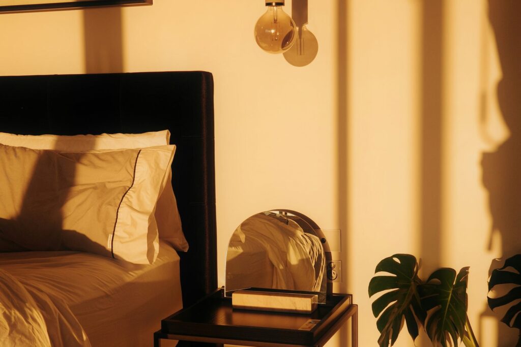 A warmly lit bedroom in the evening, made up and ready for rest.