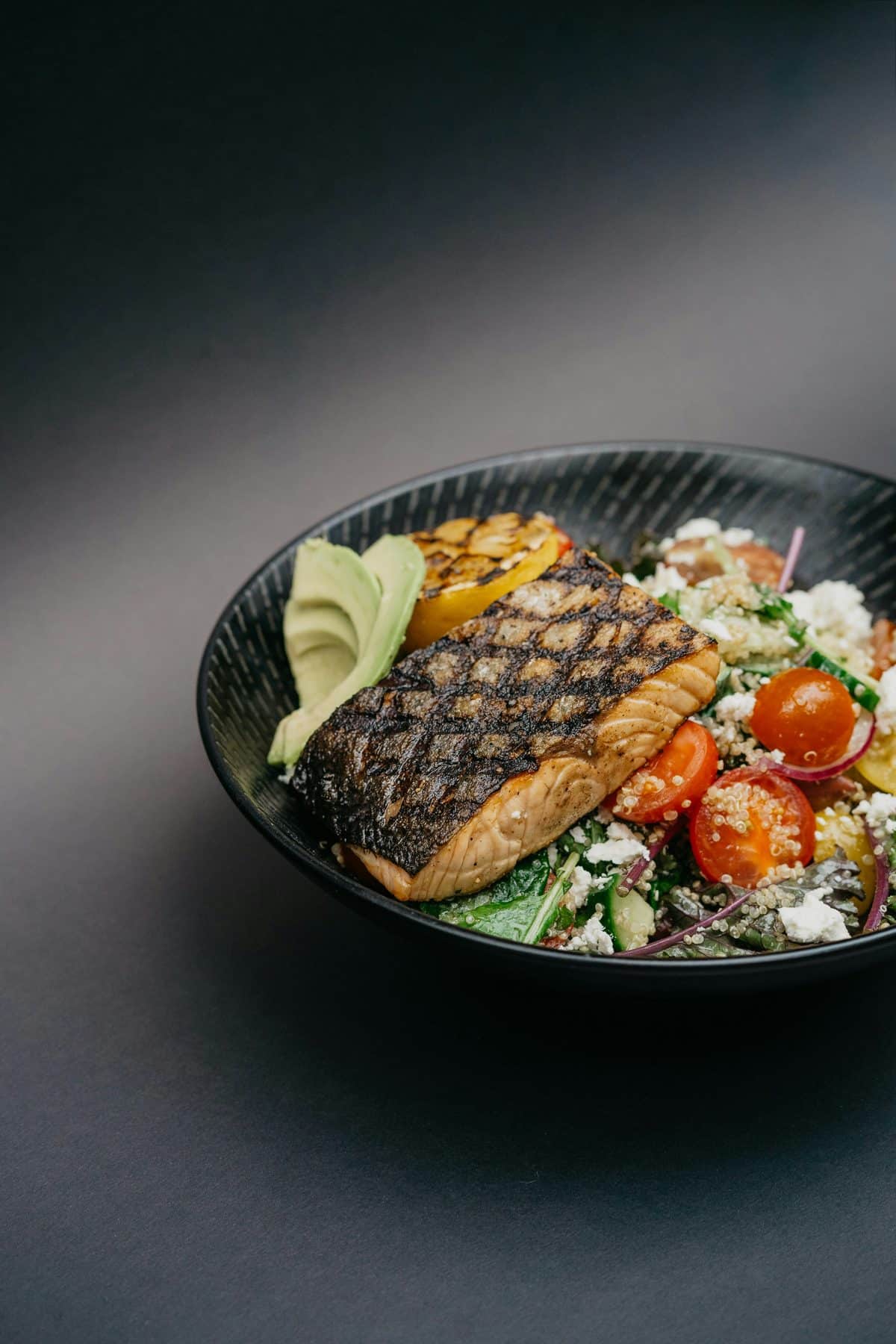 A salmon salad bowl with fresh vegetables and grains.