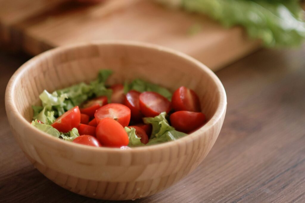 A wooden bowl of fresh salad on a kitchen worktop.