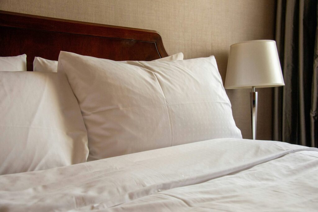 A bed with pillows propped up in a softly lit bedroom.