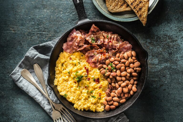 A cooked breakfast of eggs, bacon and beans in a pan.