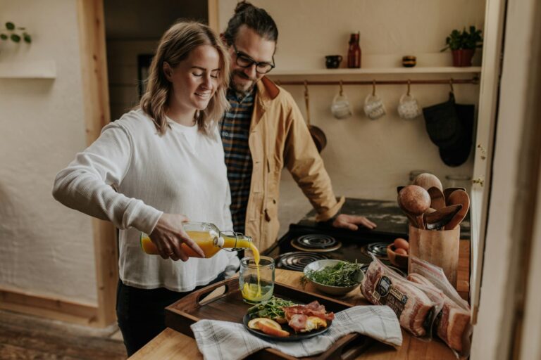 A couple preparing food together in a warm kitchen.