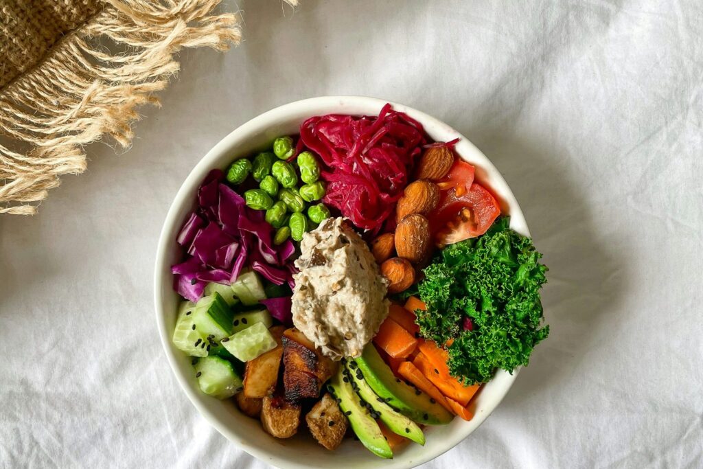 A colourful bowl of chickpeas, roasted vegetables and hummus.