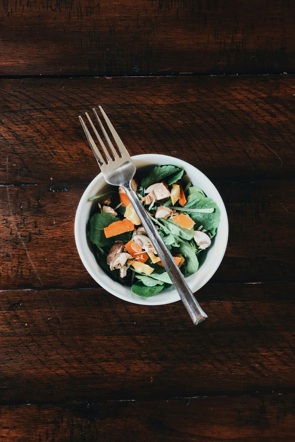 A small bowl of salad on a wooden table.